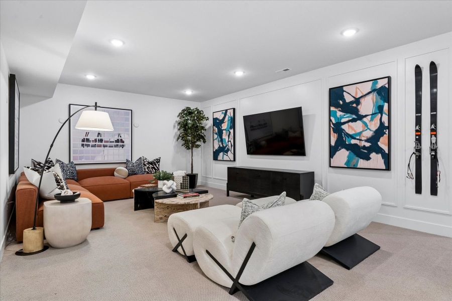 A living room with a white couch and a white wall with art.