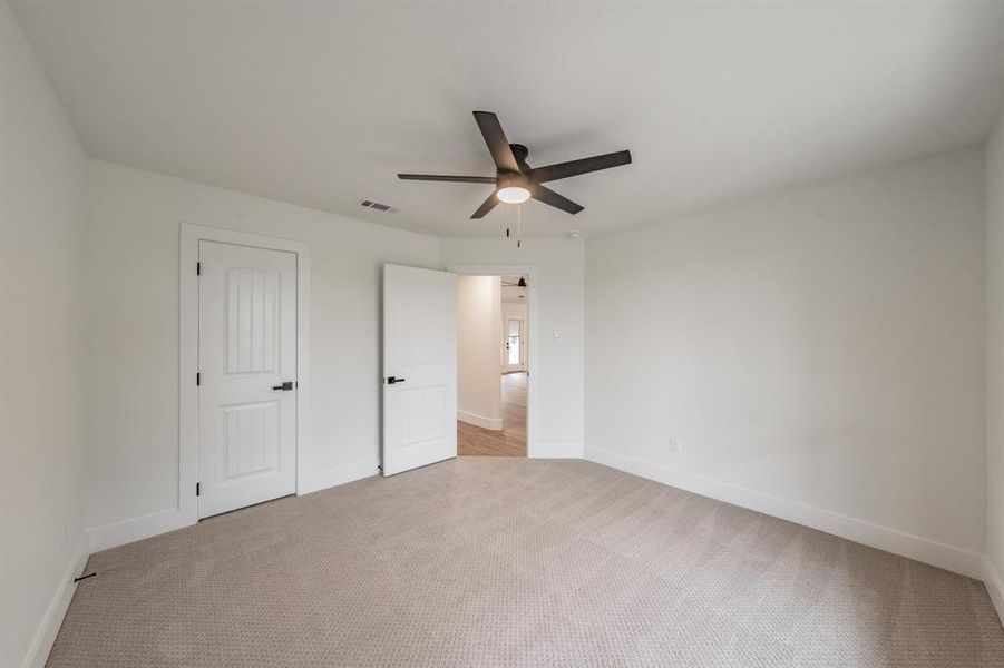 Unfurnished bedroom with light carpet, baseboards, and a ceiling fan