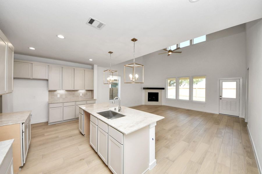 This generously spacious kitchen is a dream realized! With a massive granite island, high ceilings, soft close cabinets, granite countertops, stainless steel appliances, a sleek tile backsplash, recessed lighting, and an extended counter area, it offers both style and practicality. All this opens up to the expansive family room, creating a perfect hub for gatherings. Sample photo of completed home with similar floor plan. Actual colors and selections may vary.