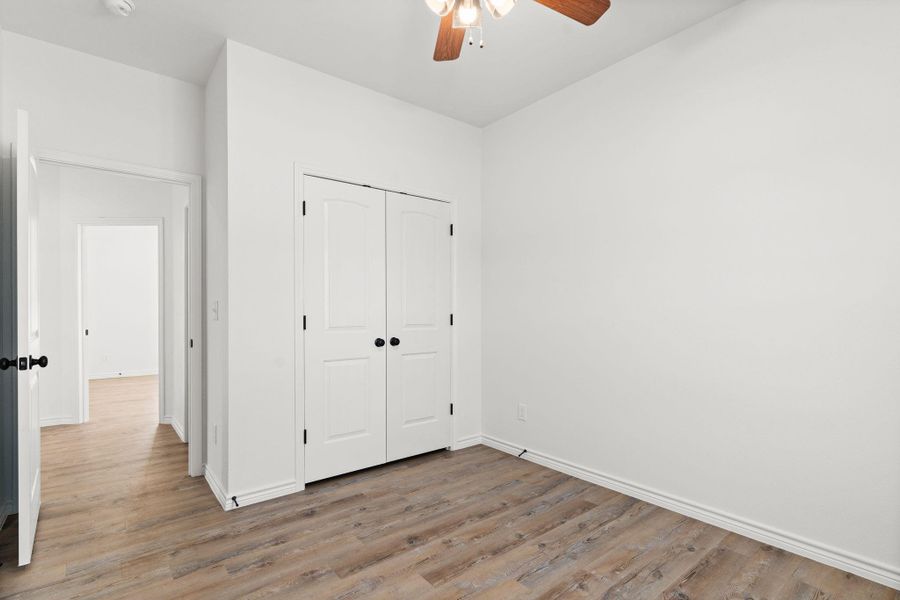 Unfurnished bedroom featuring wood finished floors, a closet, a ceiling fan, and baseboards Unfurnished bedroom featuring wood finished floors, a closet, a ceiling fan, and baseboards