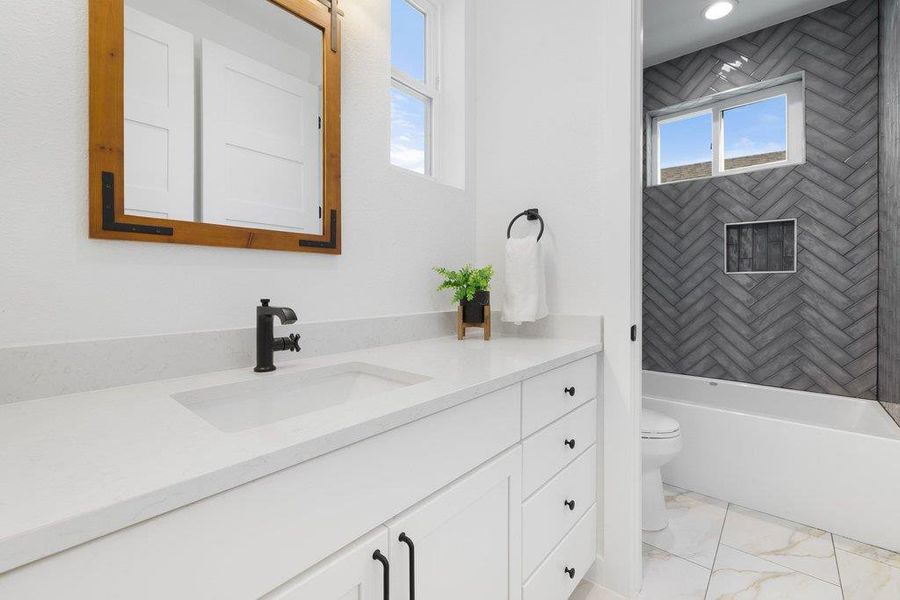 Full bath featuring vanity, washtub / shower combination, and light marble finish floors