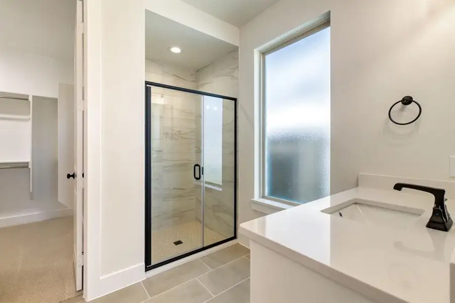 Full bath with vanity, a marble finish shower, and light tile patterned floors Full bath with vanity, a marble finish shower, and light tile patterned floors