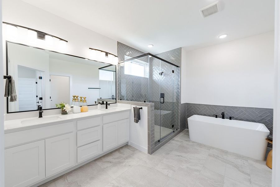 Spa inspired primary bathroom featuring a freestanding bath, double vanity, an oversized shower with bench seat, tile accent walls, and recessed lighting