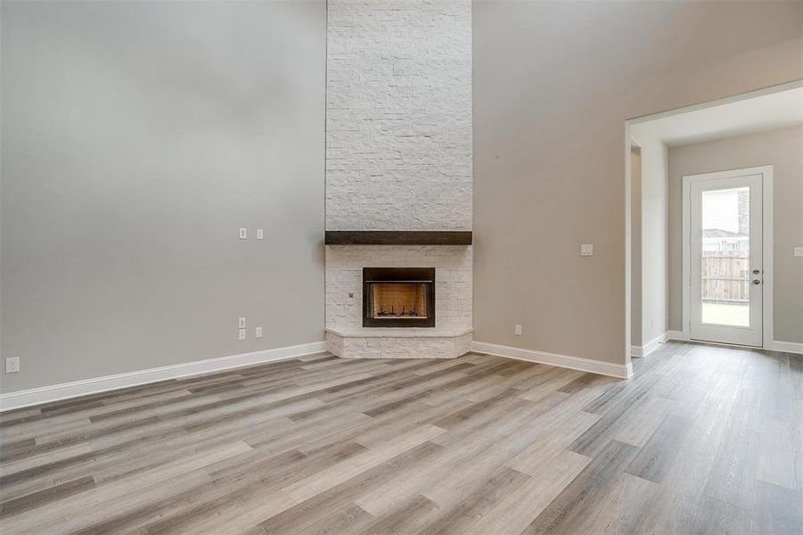 Unfurnished living room with a stone fireplace and hardwood / wood-style flooring