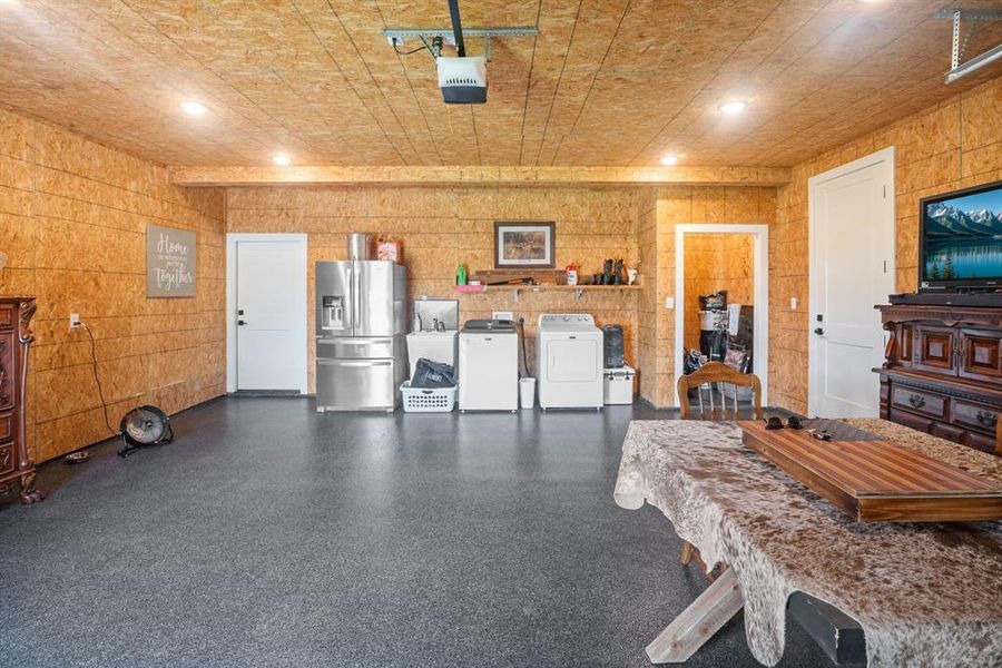 Garage featuring stainless steel fridge, a garage door opener, separate washer and dryer, recessed lighting, and a sink Garage featuring stainless steel fridge, a garage door opener, separate washer and dryer, recessed lighting, and a sink