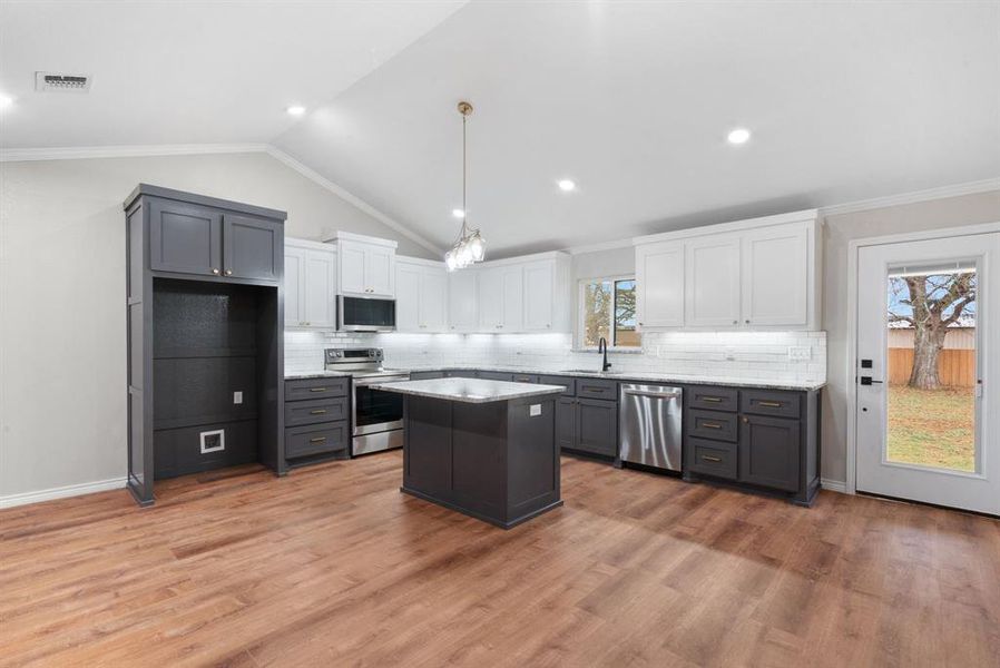 Kitchen with white cabinetry, a center island, sink, tasteful backsplash, and appliances with stainless steel finishes Kitchen with white cabinetry, a center island, sink, tasteful backsplash, and appliances with stainless steel finishes