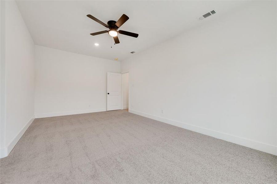 Empty room with baseboards, visible vents, a ceiling fan, and light colored carpet