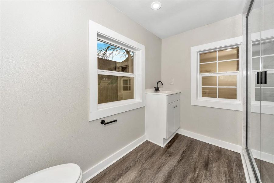 Bathroom with vanity, wood finished floors, toilet, and baseboards