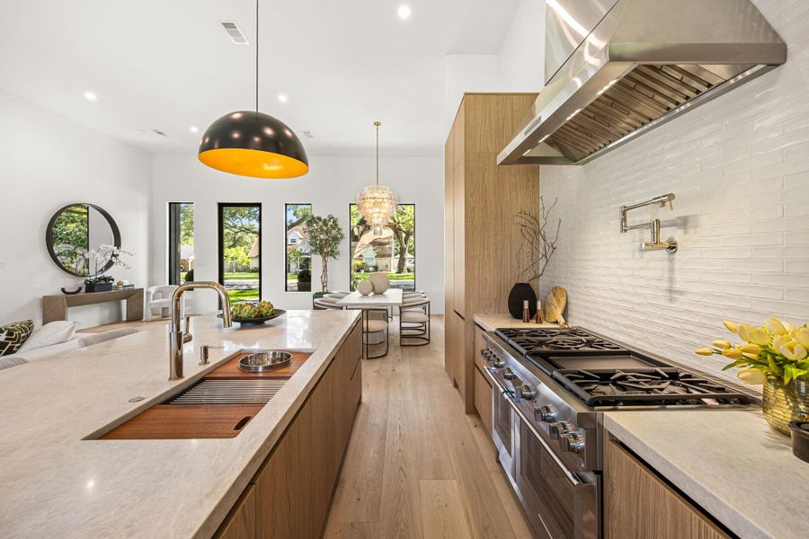 The Chef's Kitchen offers a high-end extra large quartz island, custom on-site cabinetry, a full Thermador appliance package (48in gas range & fridge w/ built-in coffee maker), pot filler & a secret entrance to the butler's pantry.