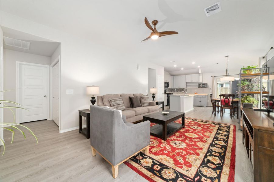 Bright open living area with high ceilings and a ceiling fan, seamlessly flowing into the kitchen and dining spaces for easy everyday living.