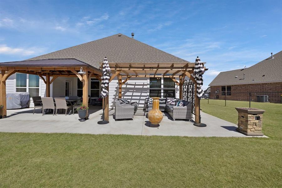 Rear view of property with a shingled roof, a patio area, a pergola, and an outdoor living space Rear view of property with a shingled roof, a patio area, a pergola, and an outdoor living space