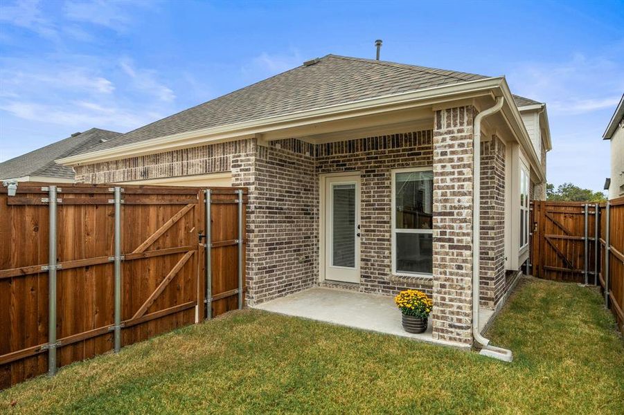 Back of house featuring a gate, a patio area, a fenced backyard, and brick siding Back of house featuring a gate, a patio area, a fenced backyard, and brick siding