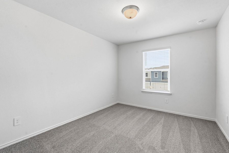 Light-filled room featuring neutral wall paint, gray carpet flooring, a single window with blinds, and a ceiling-mounted light fixture Light-filled room featuring neutral wall paint, gray carpet flooring, a single window with blinds, and a ceiling-mounted light fixture