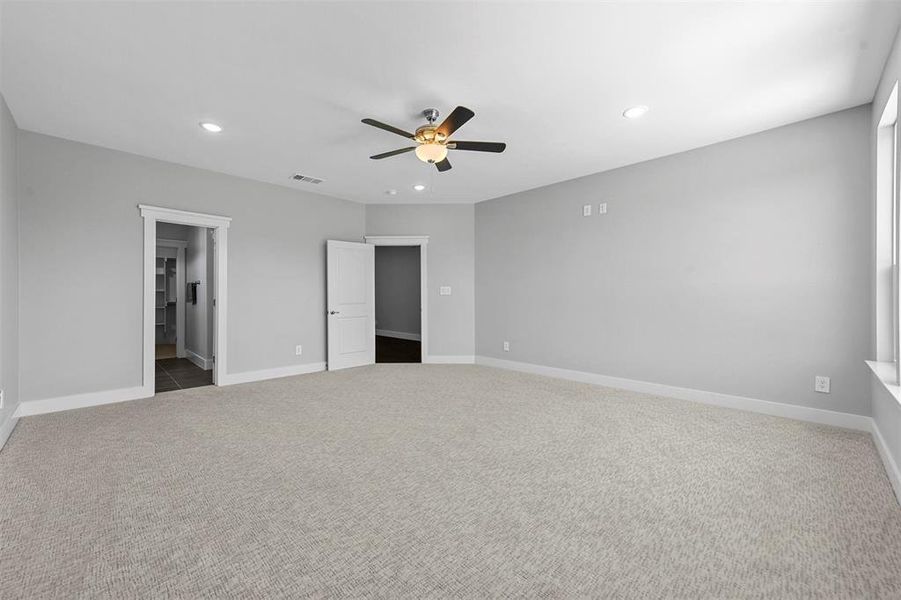 Unfurnished bedroom with ceiling fan, carpet floors, and ensuite bath