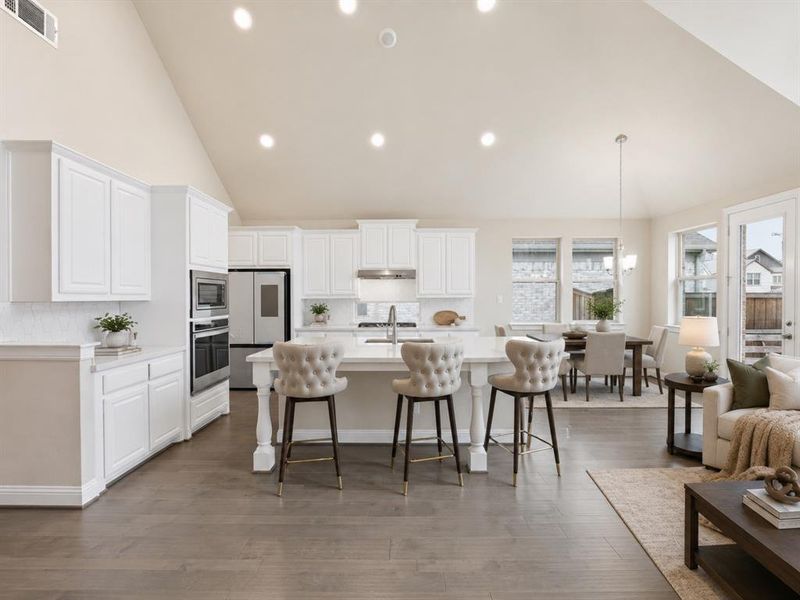 Open-concept living space featuring a vaulted ceiling and wood-finish flooring Open-concept living space featuring a vaulted ceiling and wood-finish flooring