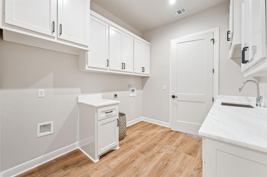 Laundry room featuring sink, light wood-type flooring, hookup for an electric dryer, and washer hookup