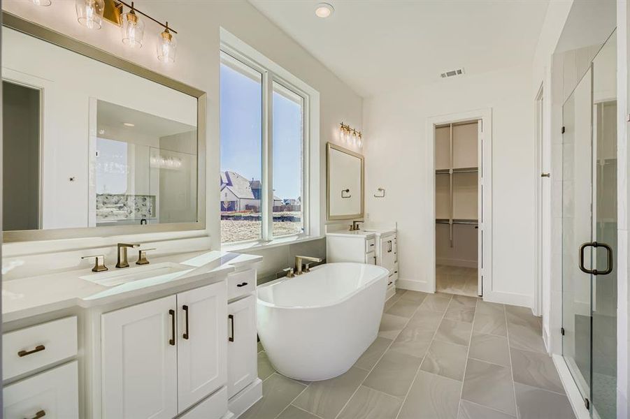 Full bathroom featuring a soaking tub, a walk in closet, two vanities, and a shower stall Full bathroom featuring a soaking tub, a walk in closet, two vanities, and a shower stall
