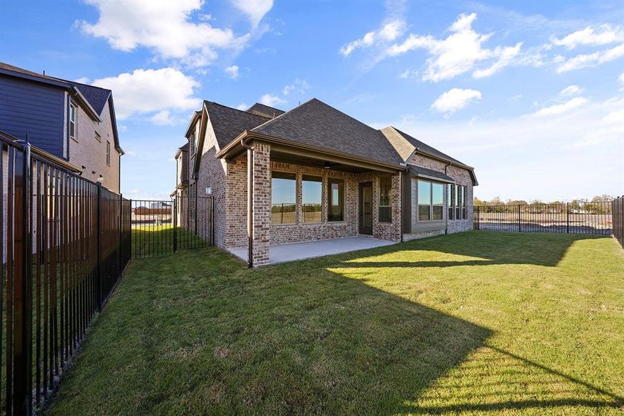 Back of property featuring roof with shingles, brick siding, a fenced backyard, and a patio
