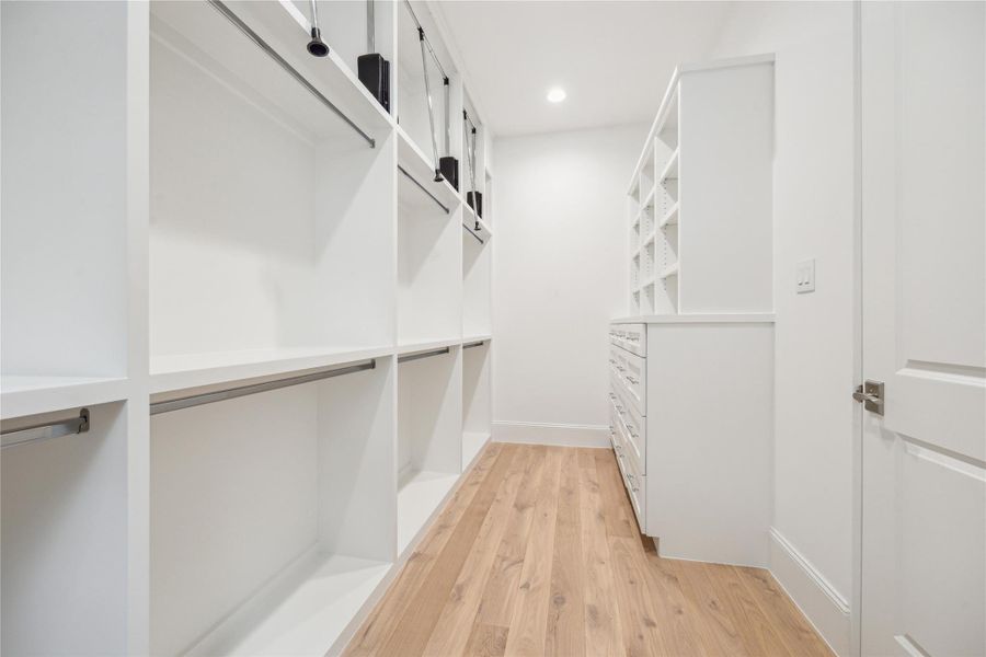 Spacious primary closet features built-in storage and ample room for hanging clothes with pull-down bars for accessing all custom storage solutions. Spacious primary closet features built-in storage and ample room for hanging clothes with pull-down bars for accessing all custom storage solutions.