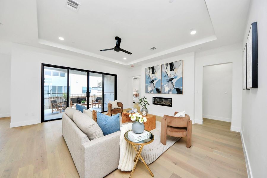 The living room exudes elegance with its tray ceilings, a sleek electric fireplace, and sliding doors that seamlessly connect indoor comfort with outdoor living.