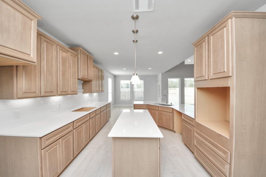 This kitchen is truly a chef's dream! This haven Boasts high ceilings, recessed & pendant lighting, stained wood cabinets, granite countertops, stainless steel appliances, a modern tile backsplash.  All of this overlooks your expansive family room, creating a perfect space for culinary delights and family gatherings.