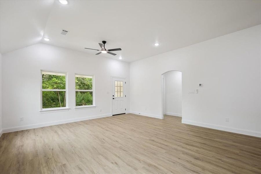 Unfurnished living room featuring light wood-style floors, arched walkways, recessed lighting, ceiling fan, and vaulted ceiling Unfurnished living room featuring light wood-style floors, arched walkways, recessed lighting, ceiling fan, and vaulted ceiling