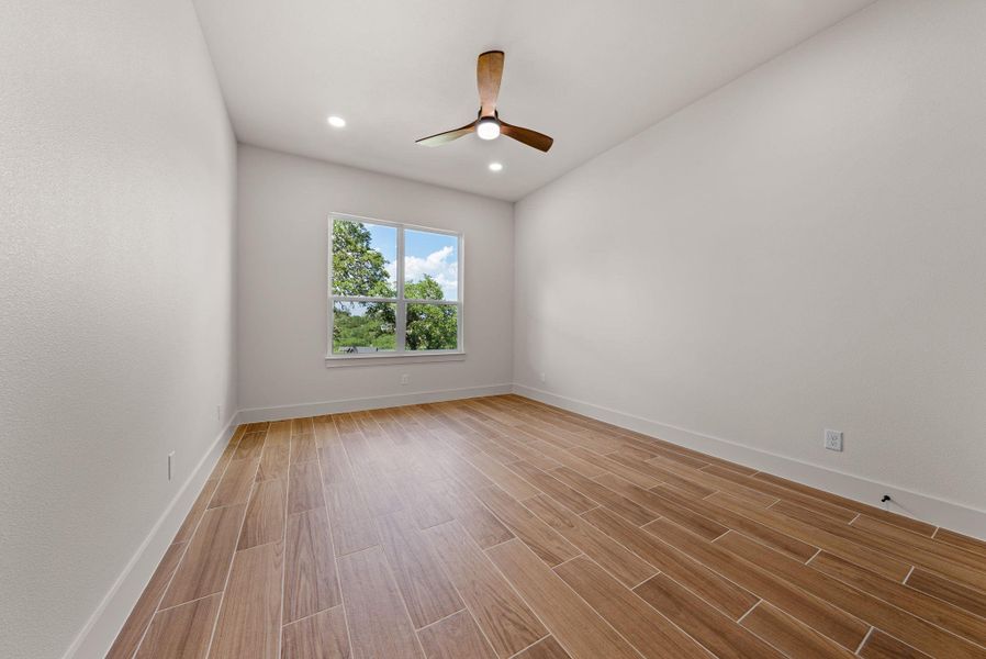 A quiet space with sleek wood flooring and a modern ceiling fan, offering a serene view through a large window.