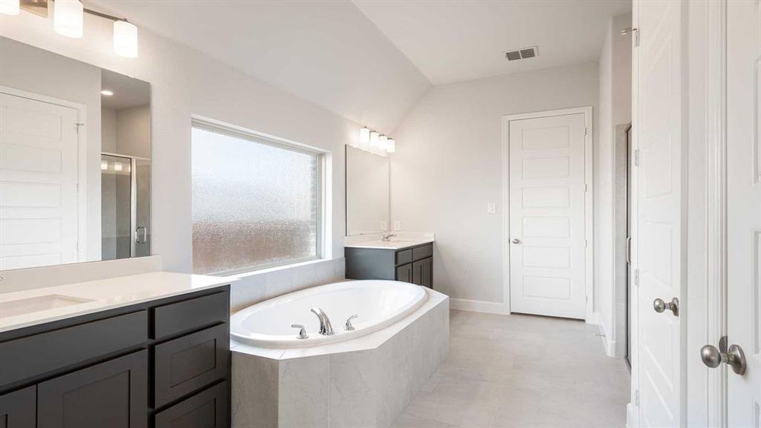 Bathroom with vanity, vaulted ceiling, and plus walk in shower