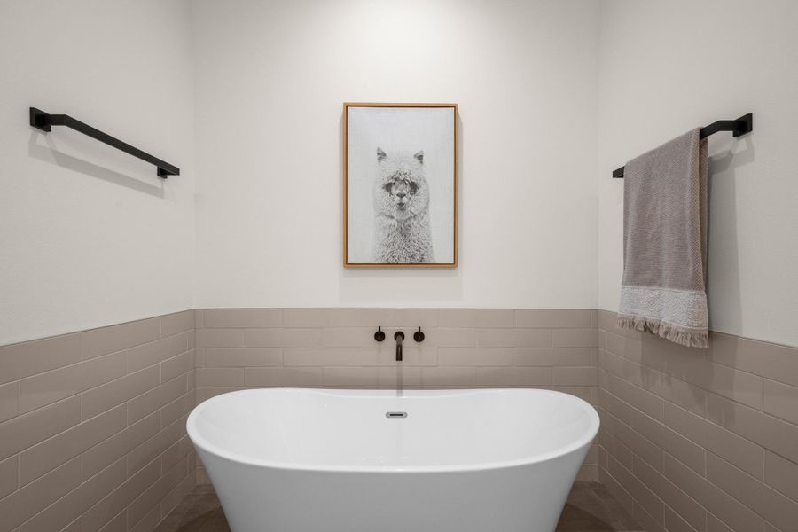 Bathroom with tile walls, wainscoting, and a soaking tub