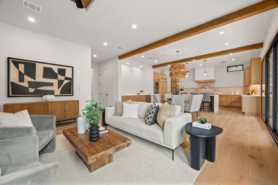 Rich wood beams span the ceiling of this sprawling open-concept living area with hardwood floors.