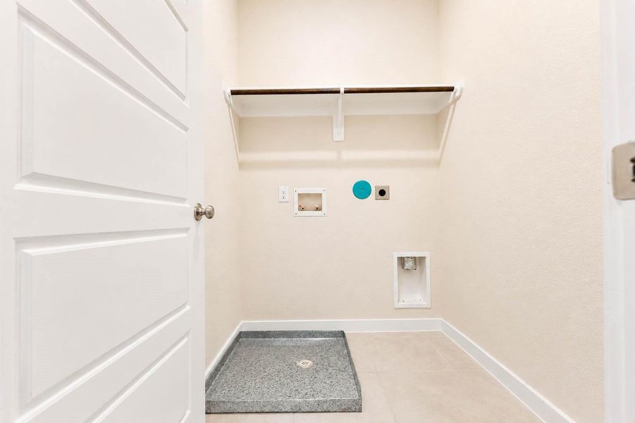 Dedicated laundry room provides convenient washer and dryer connections, tile flooring, and built-in shelving with a hanging rod for additional organization. The practical layout offers space for laundry essentials, storage, and garment care while keeping household tasks neatly contained in one designated area. Dedicated laundry room provides convenient washer and dryer connections, tile flooring, and built-in shelving with a hanging rod for additional organization. The practical layout offers space for laundry essentials, storage, and garment care while keeping household tasks neatly contained in one designated area.