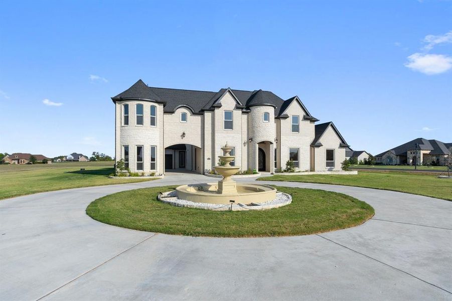 French country home featuring a front yard, curved driveway, and a residential view