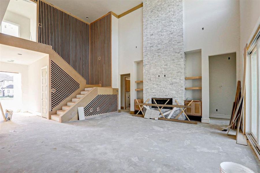 Living room with a fireplace, a high ceiling, and built in shelves