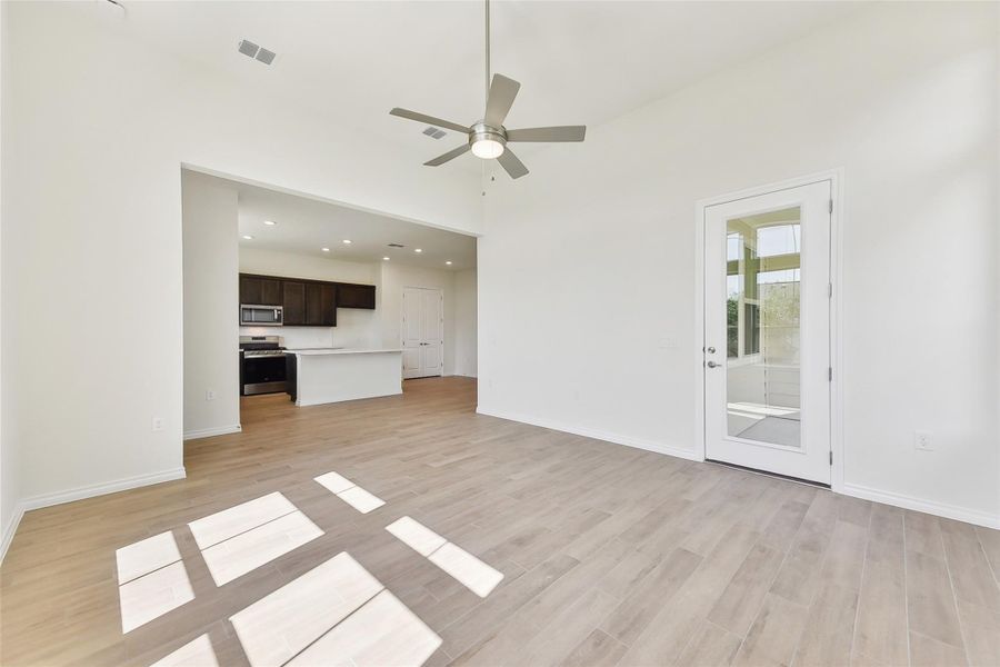 Unfurnished living room with light wood finished floors, baseboards, a ceiling fan, and visible vents Unfurnished living room with light wood finished floors, baseboards, a ceiling fan, and visible vents