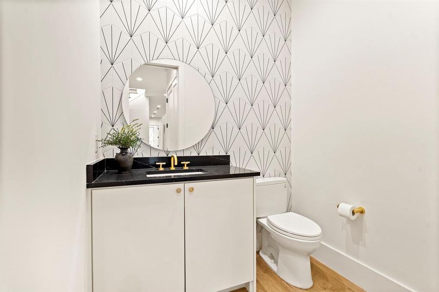 Bathroom with wallpapered walls, vanity, and wood finished floors Bathroom with wallpapered walls, vanity, and wood finished floors