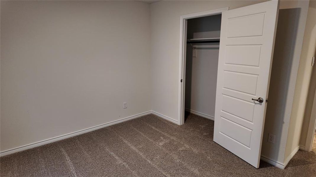 Unfurnished bedroom featuring dark carpet and a closet