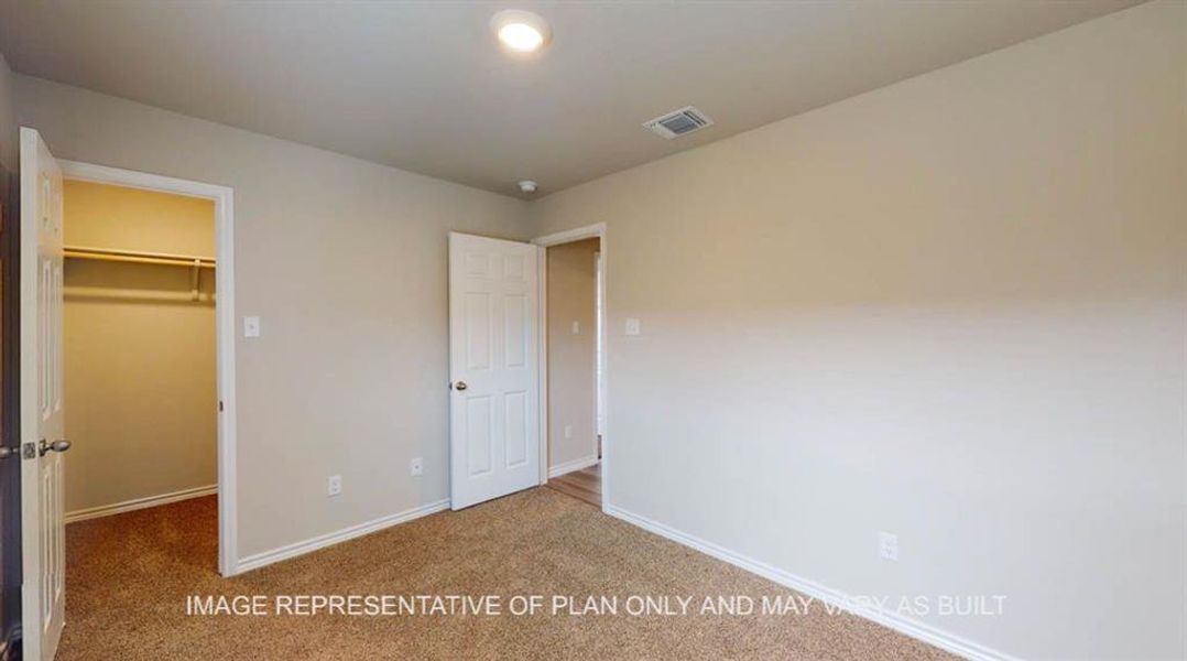 Unfurnished bedroom with a spacious closet and carpet Unfurnished bedroom with a spacious closet and carpet