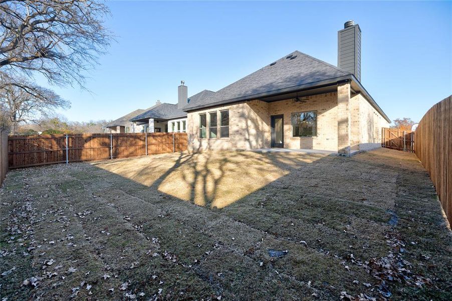 Rear view of house with ceiling fan and a lawn