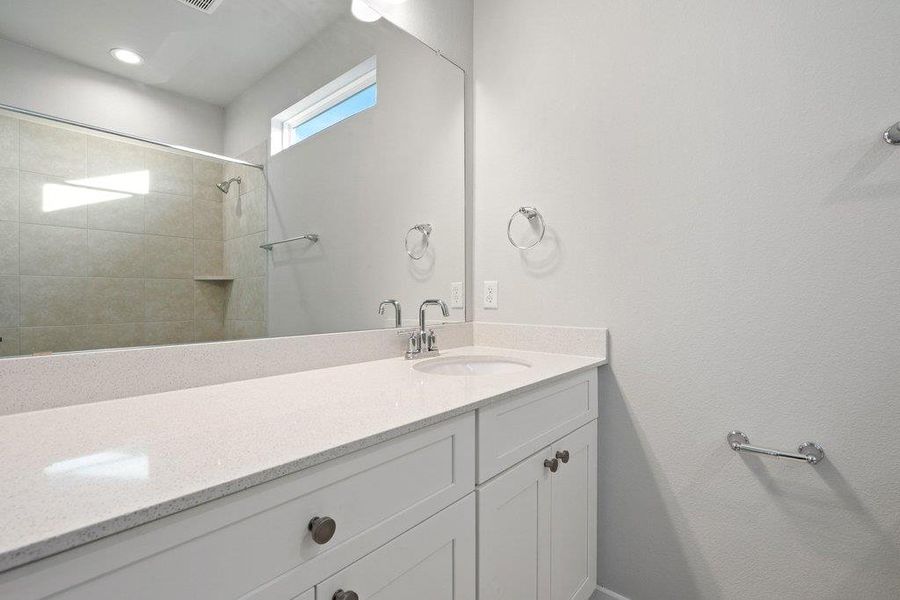 Bathroom with vanity and tiled shower
