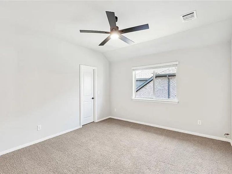 Unfurnished room with carpet floors, ceiling fan, baseboards, and vaulted ceiling