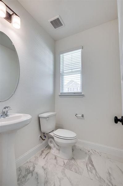 Half bathroom featuring toilet and marble finish floors Half bathroom featuring toilet and marble finish floors