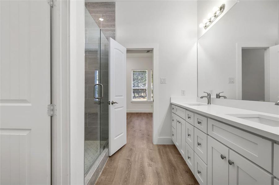 Bathroom featuring hardwood / wood-style floors, vanity, and a shower with shower door