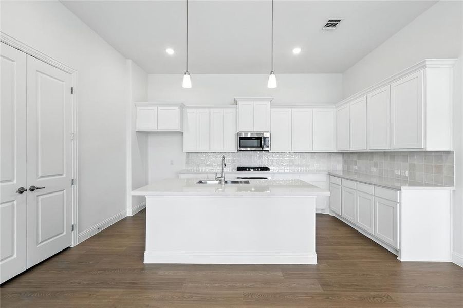 Kitchen with white cabinetry, decorative backsplash, dark wood-type flooring, stainless steel microwave, and recessed lighting