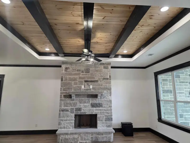 Unfurnished living room with recessed lighting, a ceiling fan, a stone fireplace, wood finished floors, and a wooden ceiling with exposed beams Unfurnished living room with recessed lighting, a ceiling fan, a stone fireplace, wood finished floors, and a wooden ceiling with exposed beams