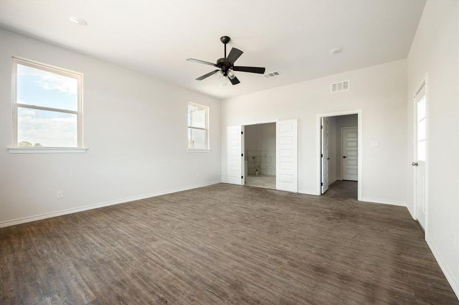 Unfurnished bedroom featuring ensuite bathroom, dark hardwood / wood-style floors, and ceiling fan