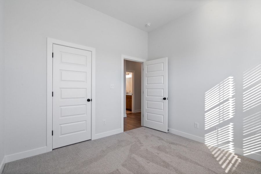 Neutral wall paint, plush carpet flooring, recessed ceiling lighting, five-panel interior doors with black hardware