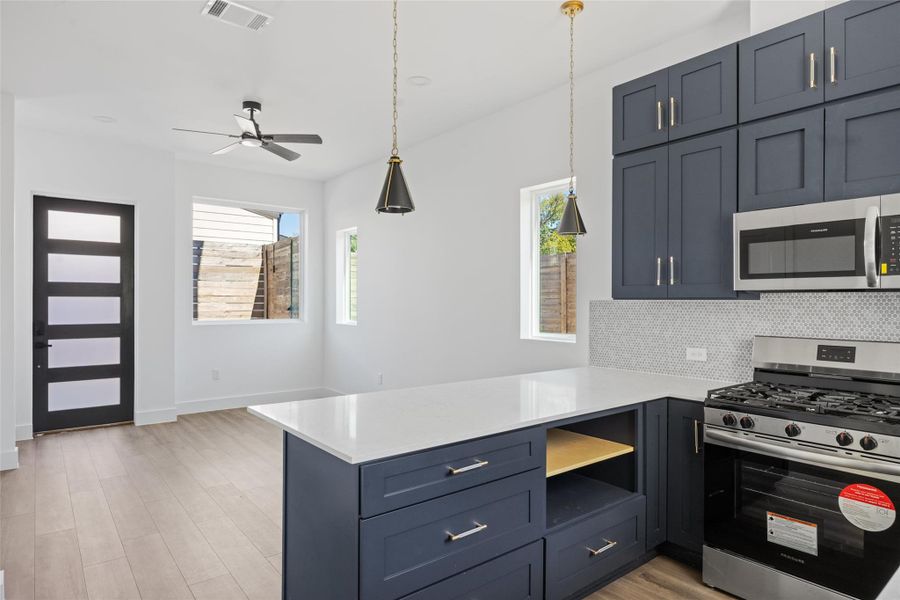 Kitchen with stainless steel appliances, light stone countertops, light wood-style floors, and a peninsula Kitchen with stainless steel appliances, light stone countertops, light wood-style floors, and a peninsula