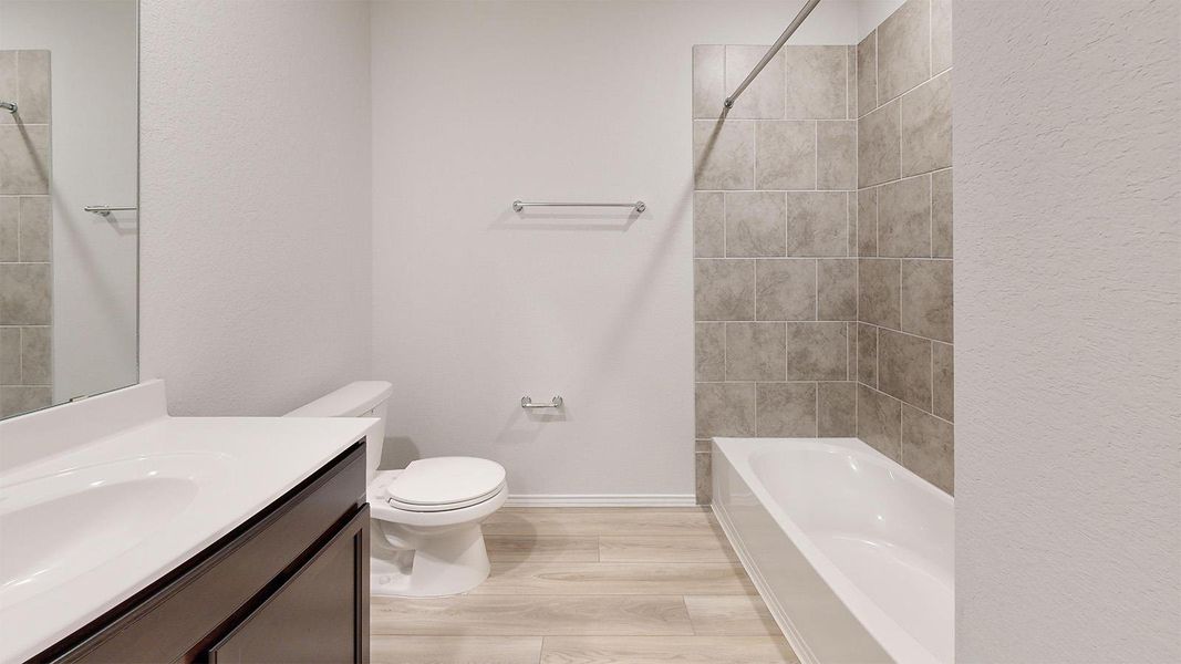 A well-appointed bath features a sleek vanity and a tiled tub-shower combination.