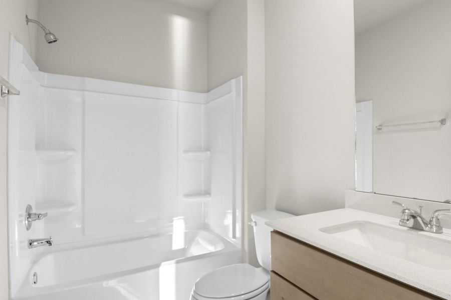 Image of a bathroom with brown cabinets and a white vanity with a white vinyl shower and tub