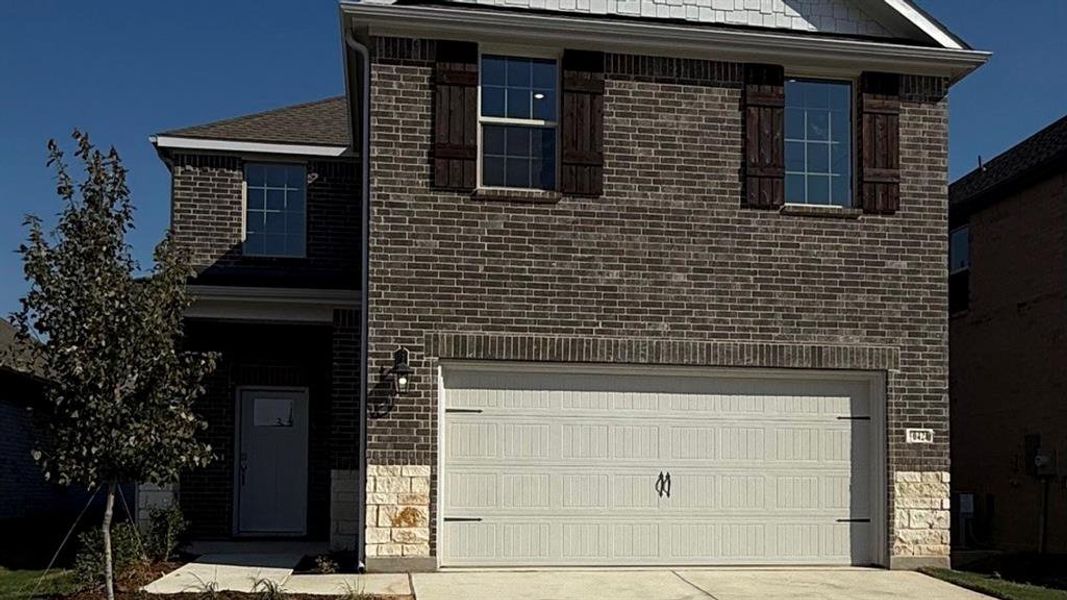 Traditional-style house featuring brick siding, concrete driveway, and an attached garage